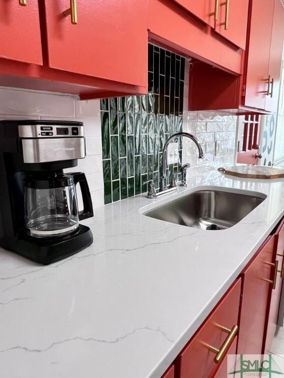 kitchen featuring light stone countertops, sink, and decorative backsplash