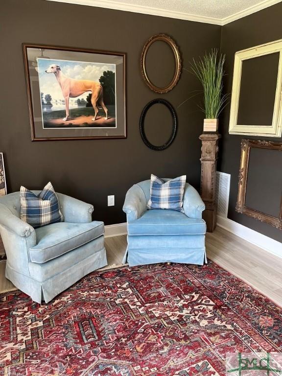 living room featuring ornamental molding, light hardwood / wood-style floors, and a textured ceiling