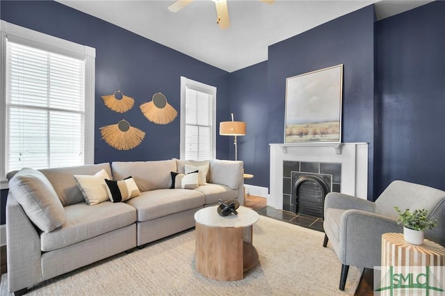 living room featuring a tiled fireplace and ceiling fan