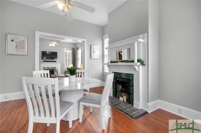 dining room with hardwood / wood-style flooring, ceiling fan, and a fireplace