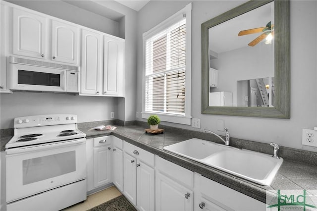 kitchen featuring white cabinetry, sink, white appliances, and a healthy amount of sunlight