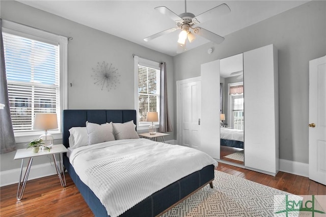 bedroom featuring dark wood-type flooring, ceiling fan, and multiple windows