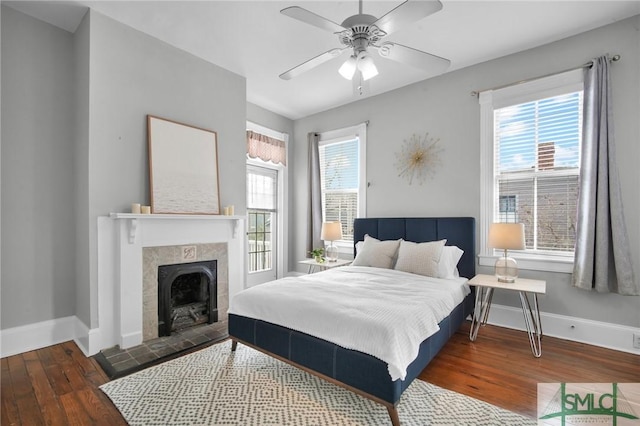 bedroom featuring a fireplace, dark wood-type flooring, and ceiling fan