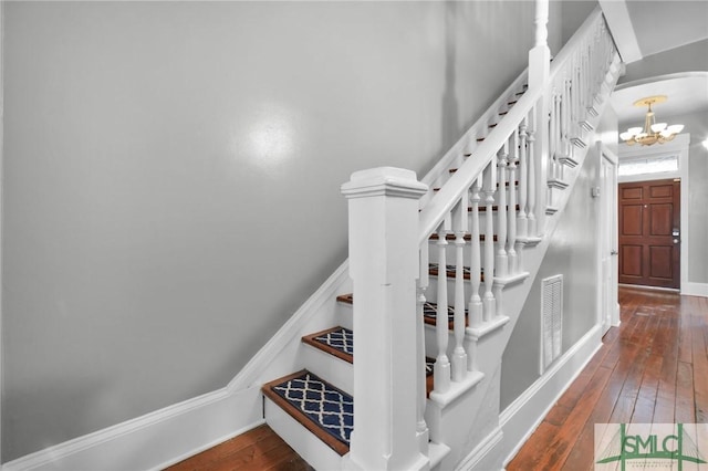 stairs featuring an inviting chandelier and hardwood / wood-style floors