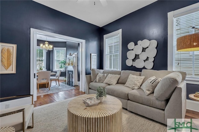 living room with ceiling fan with notable chandelier and light wood-type flooring