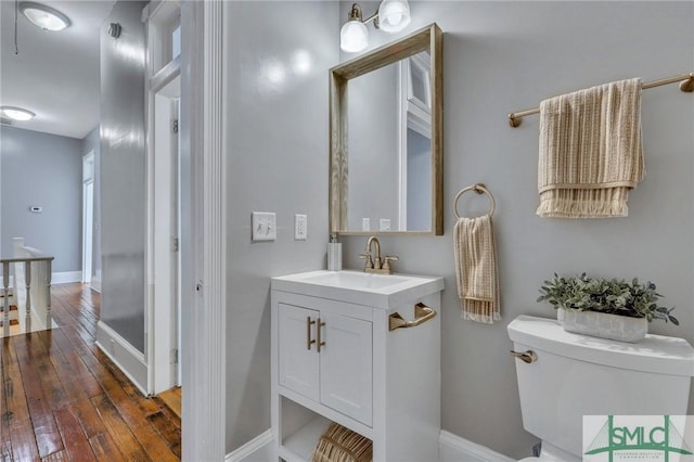 bathroom with hardwood / wood-style flooring, vanity, and toilet