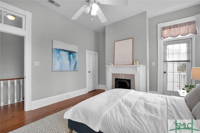 bedroom with ceiling fan, dark hardwood / wood-style floors, and a fireplace