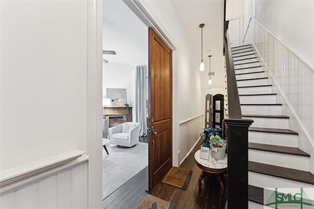 stairs featuring hardwood / wood-style flooring, a fireplace, a decorative wall, and wainscoting