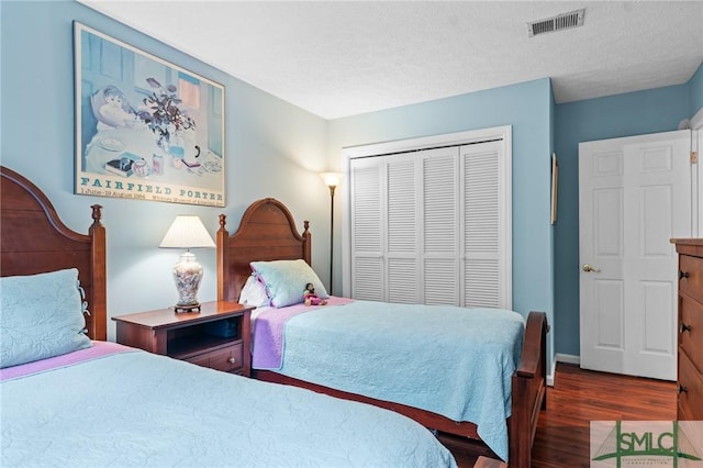 bedroom featuring dark hardwood / wood-style flooring, a closet, and a textured ceiling