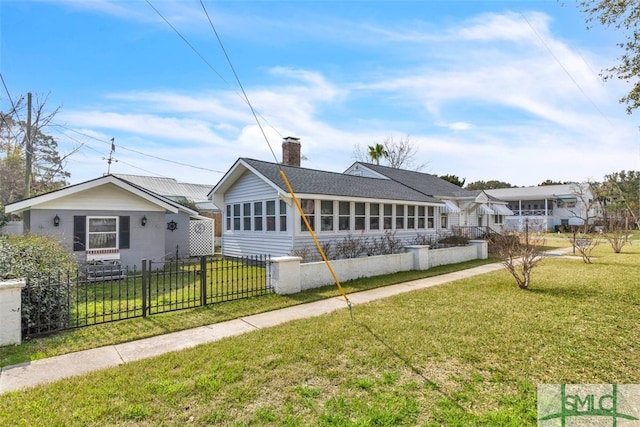 back of property with a fenced front yard, a chimney, and a lawn