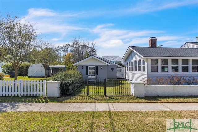 bungalow-style home with a shingled roof, a fenced front yard, a chimney, a storage unit, and a front yard