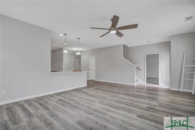 unfurnished living room with ceiling fan, sink, and light wood-type flooring