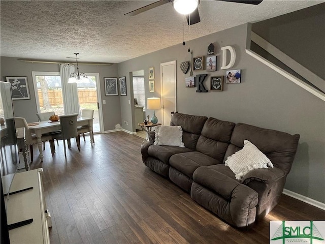 living room featuring dark hardwood / wood-style floors, ceiling fan with notable chandelier, and a textured ceiling