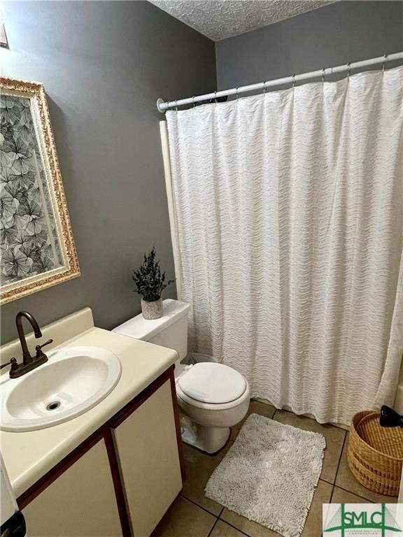 bathroom with tile patterned floors, toilet, a textured ceiling, and vanity