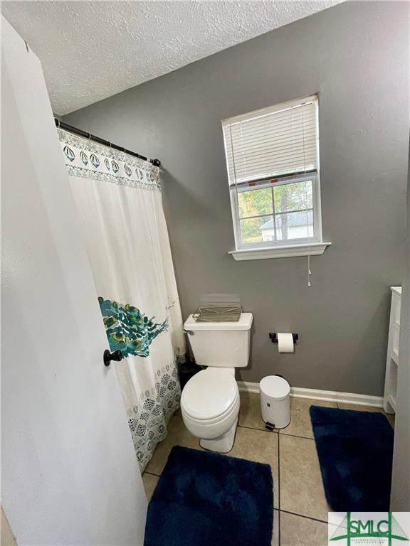 bathroom with tile patterned flooring, a textured ceiling, and toilet