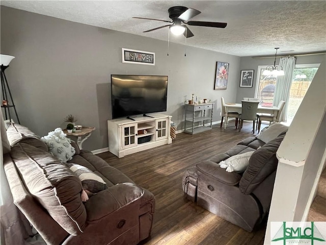 living room with dark hardwood / wood-style floors, ceiling fan with notable chandelier, and a textured ceiling