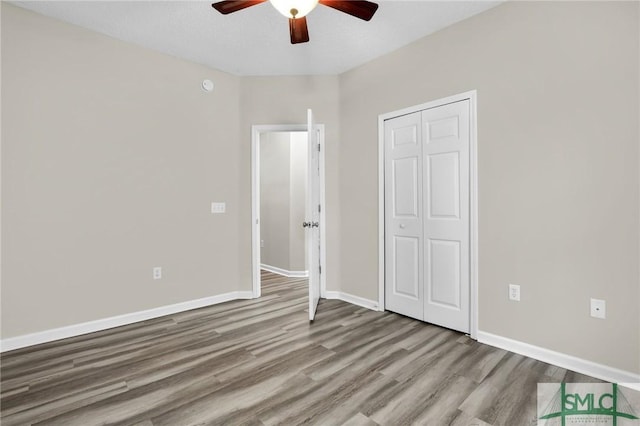 unfurnished bedroom featuring ceiling fan, a closet, and light hardwood / wood-style flooring