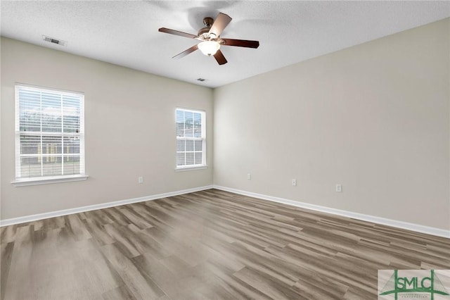 unfurnished room with a textured ceiling, wood-type flooring, and ceiling fan