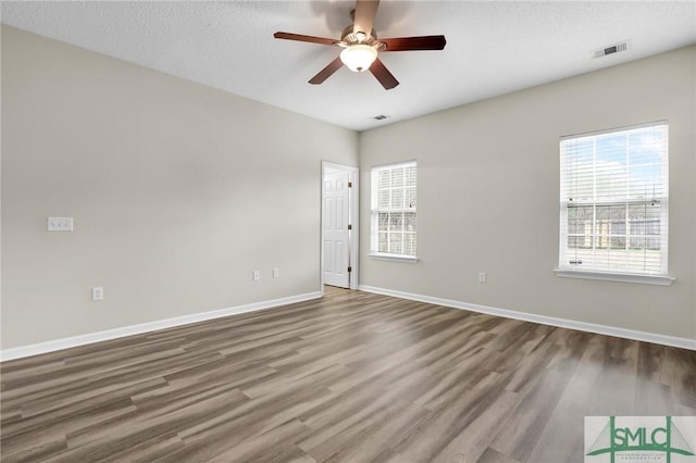 empty room featuring hardwood / wood-style flooring, plenty of natural light, and a textured ceiling