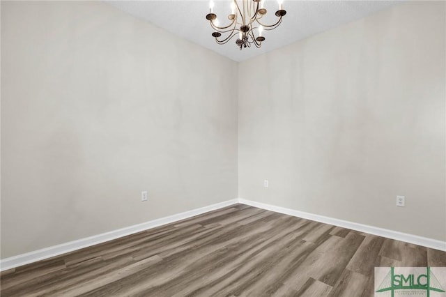 unfurnished room with hardwood / wood-style floors and an inviting chandelier