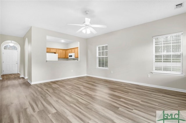 unfurnished living room featuring ceiling fan, plenty of natural light, and light hardwood / wood-style flooring