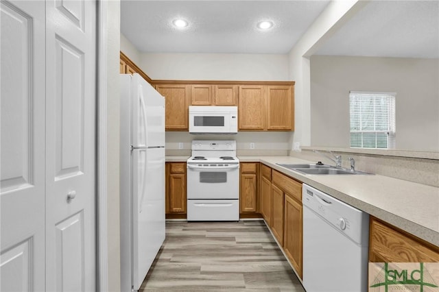 kitchen with white appliances, sink, a textured ceiling, and light wood-type flooring