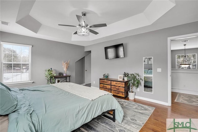 bedroom with a tray ceiling, ceiling fan, and hardwood / wood-style flooring