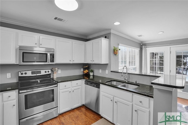 kitchen with appliances with stainless steel finishes, sink, white cabinets, ornamental molding, and kitchen peninsula