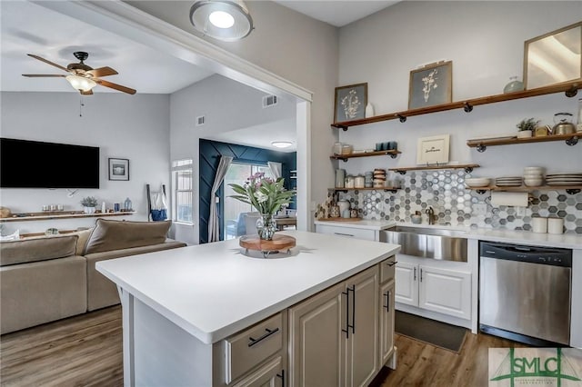 kitchen featuring sink, dishwasher, a center island, tasteful backsplash, and light wood-type flooring