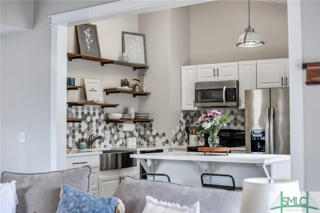 kitchen featuring sink, backsplash, stainless steel appliances, white cabinets, and decorative light fixtures