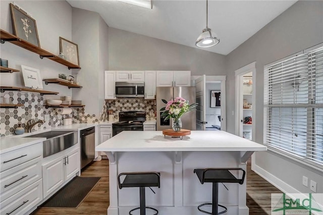 kitchen featuring appliances with stainless steel finishes, decorative light fixtures, sink, white cabinets, and a kitchen breakfast bar