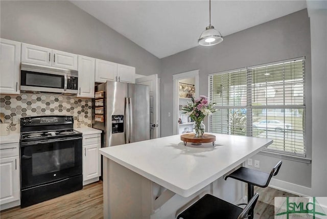 kitchen featuring white cabinetry, a kitchen bar, hanging light fixtures, and appliances with stainless steel finishes