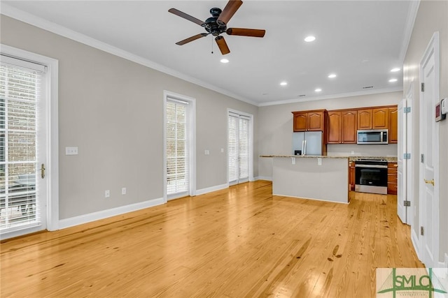 kitchen with ornamental molding, appliances with stainless steel finishes, a center island, and light wood-type flooring