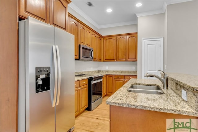 kitchen with sink, light stone counters, ornamental molding, appliances with stainless steel finishes, and light hardwood / wood-style floors