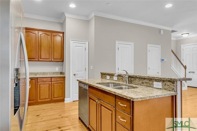 kitchen with sink, light wood-type flooring, appliances with stainless steel finishes, ornamental molding, and an island with sink