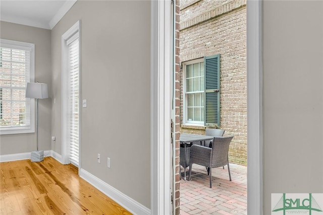 interior space featuring crown molding, wood-type flooring, and brick wall