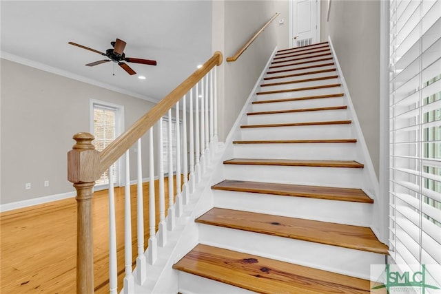 stairway with crown molding, ceiling fan, and wood-type flooring