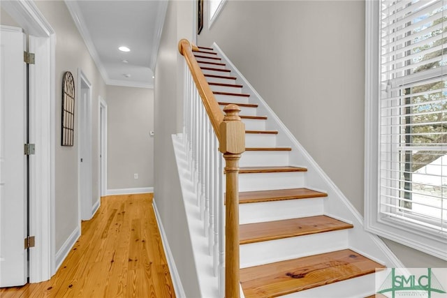 stairway featuring crown molding, a wealth of natural light, and wood-type flooring