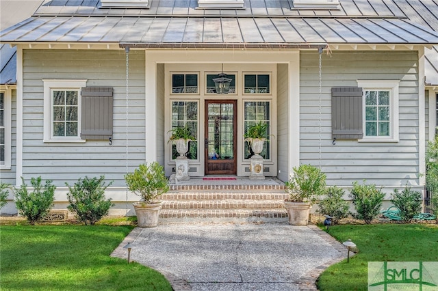 doorway to property featuring a standing seam roof, metal roof, and a yard