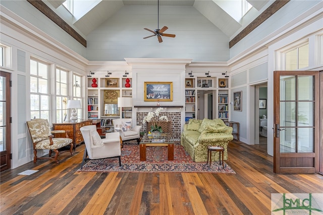 living area featuring a skylight, a fireplace, ceiling fan, high vaulted ceiling, and hardwood / wood-style flooring