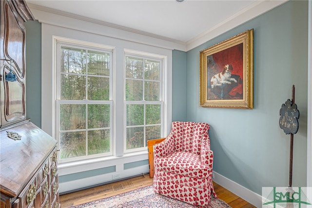 sitting room featuring plenty of natural light, crown molding, baseboards, and wood finished floors