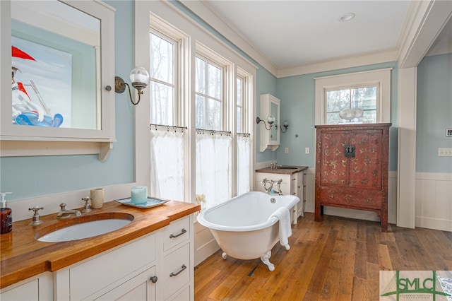 full bathroom featuring a soaking tub, crown molding, and wood finished floors