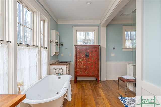 full bathroom featuring a freestanding tub, wainscoting, crown molding, and wood finished floors