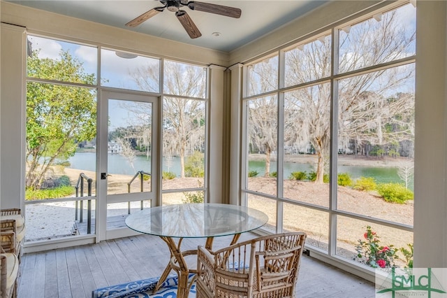 sunroom / solarium featuring a ceiling fan and a water view