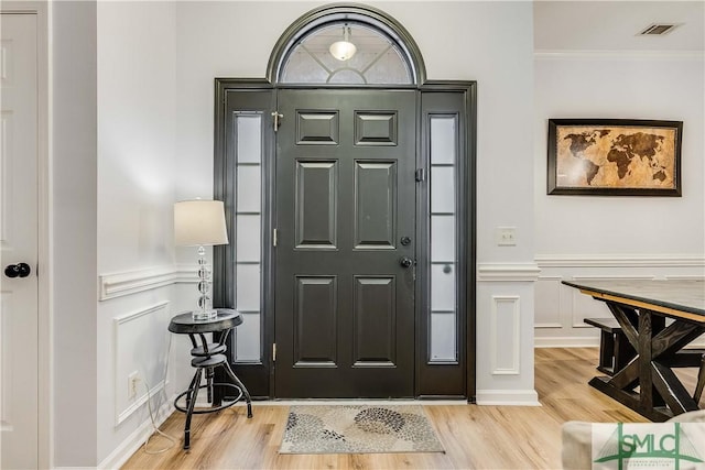 entrance foyer featuring ornamental molding and light hardwood / wood-style floors