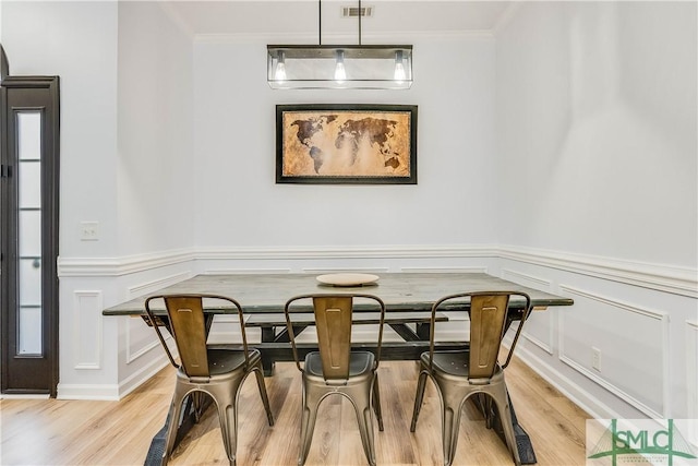 dining space featuring ornamental molding and light wood-type flooring