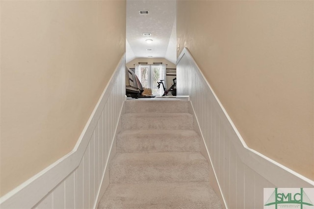 staircase featuring vaulted ceiling and carpet