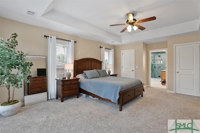 carpeted bedroom featuring ensuite bathroom, ceiling fan, and a tray ceiling