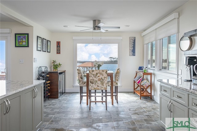 dining room featuring ceiling fan and a water view