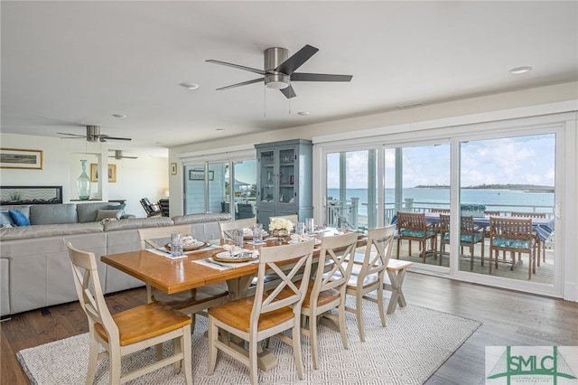 dining area featuring a water view, ceiling fan, and dark hardwood / wood-style floors